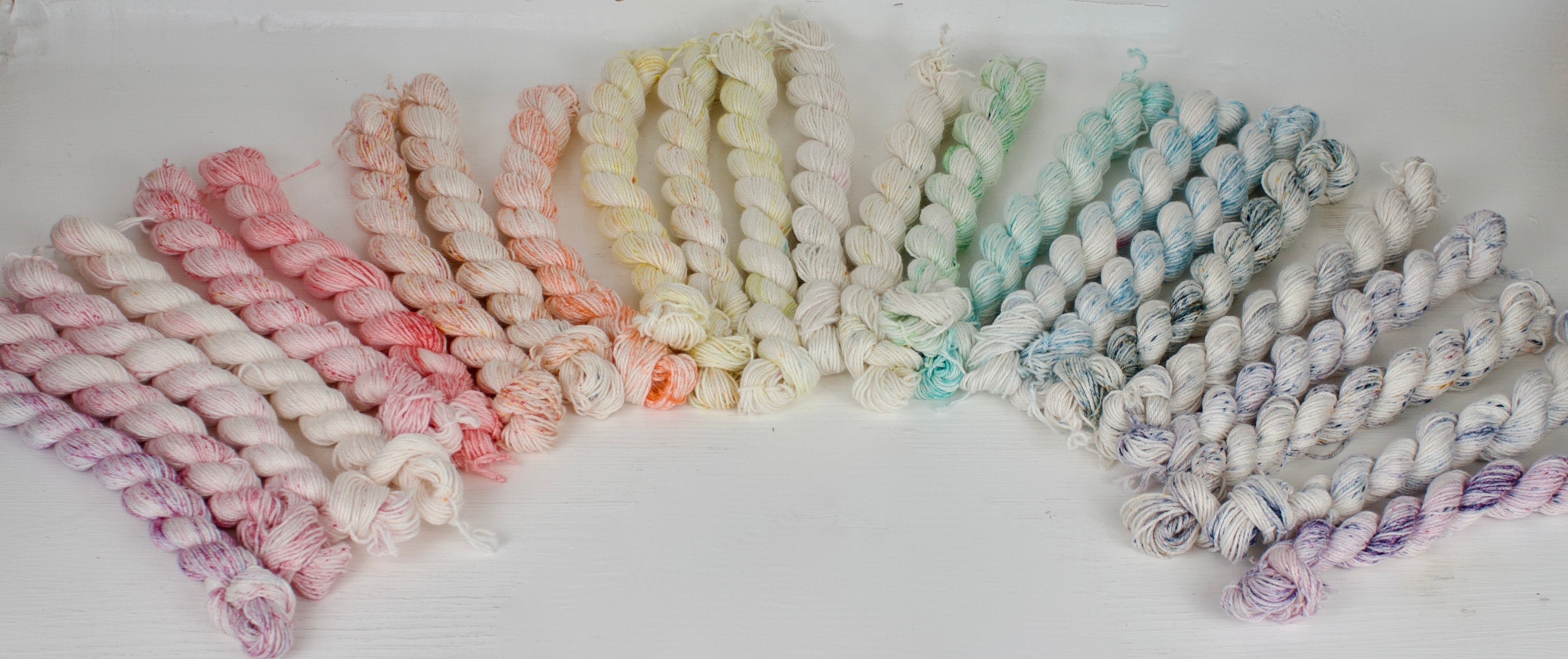 Image Banner: speckled mini skeins fanned out in a rainbow, yarn shown is from the festive calendar kit