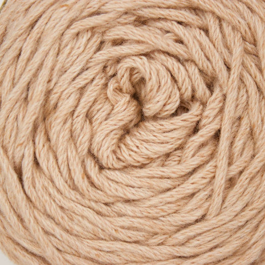 A close-up of a coiled ball of natural beige cotton yarn against a plain white background.