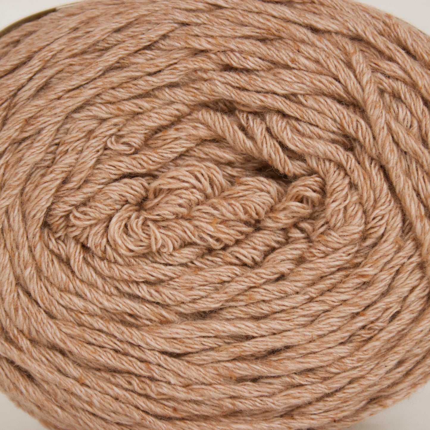 A close-up of a large ball of twisted yarn in a warm tan or camel shade, photographed against a plain light background.
