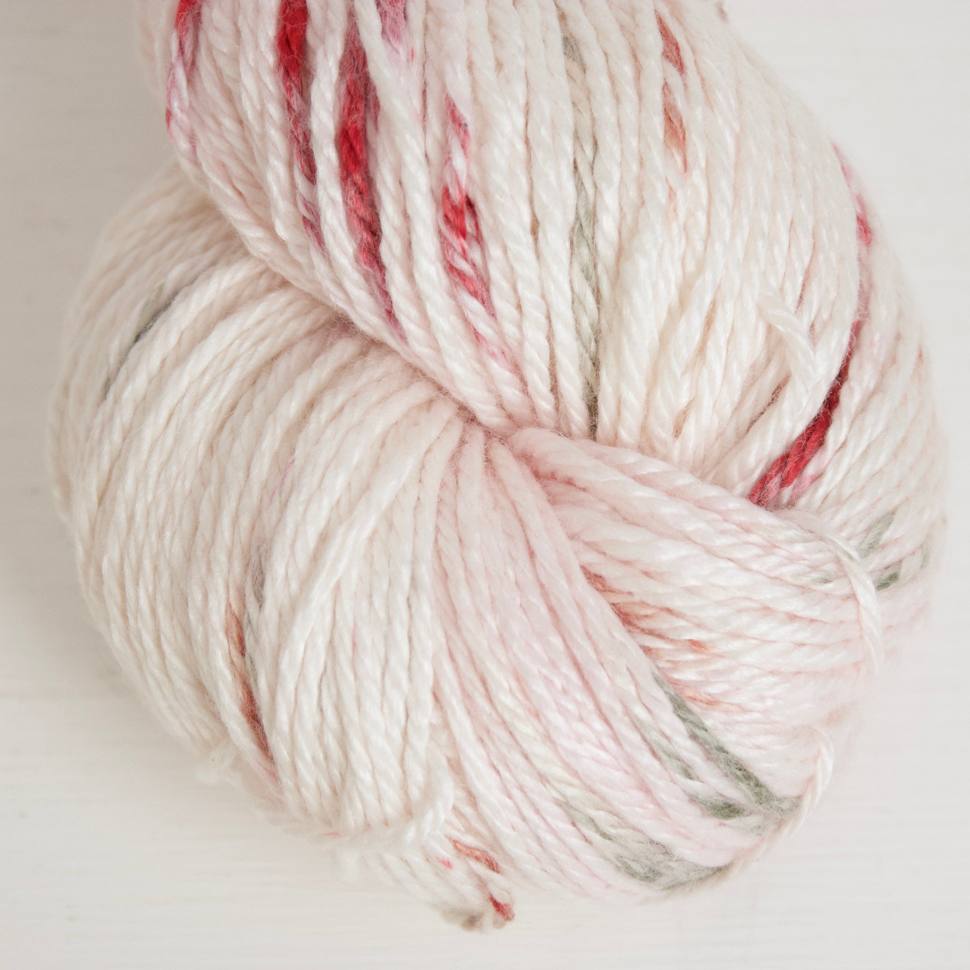 Cinnamon Sage Rose on Alnilam is a creamy white base with tints of light pink and dashes of red-brown, and burgundy with purple halos, and strikes of sage green.