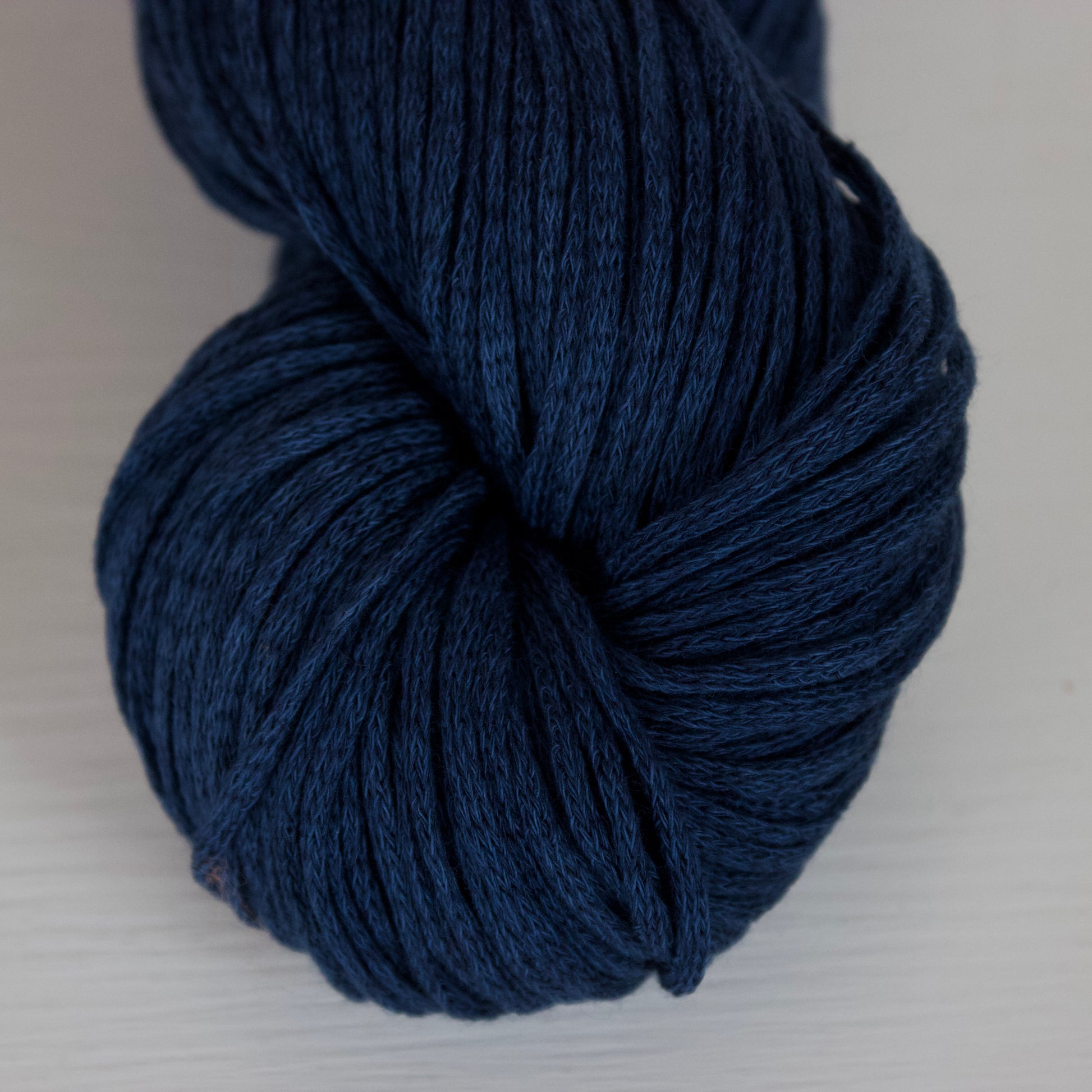 Close up of a skein of rich blue yarn called Cobalt, this is on an aran weight yarn called Taika which is tubular knit and has a semi glossy surface. 
