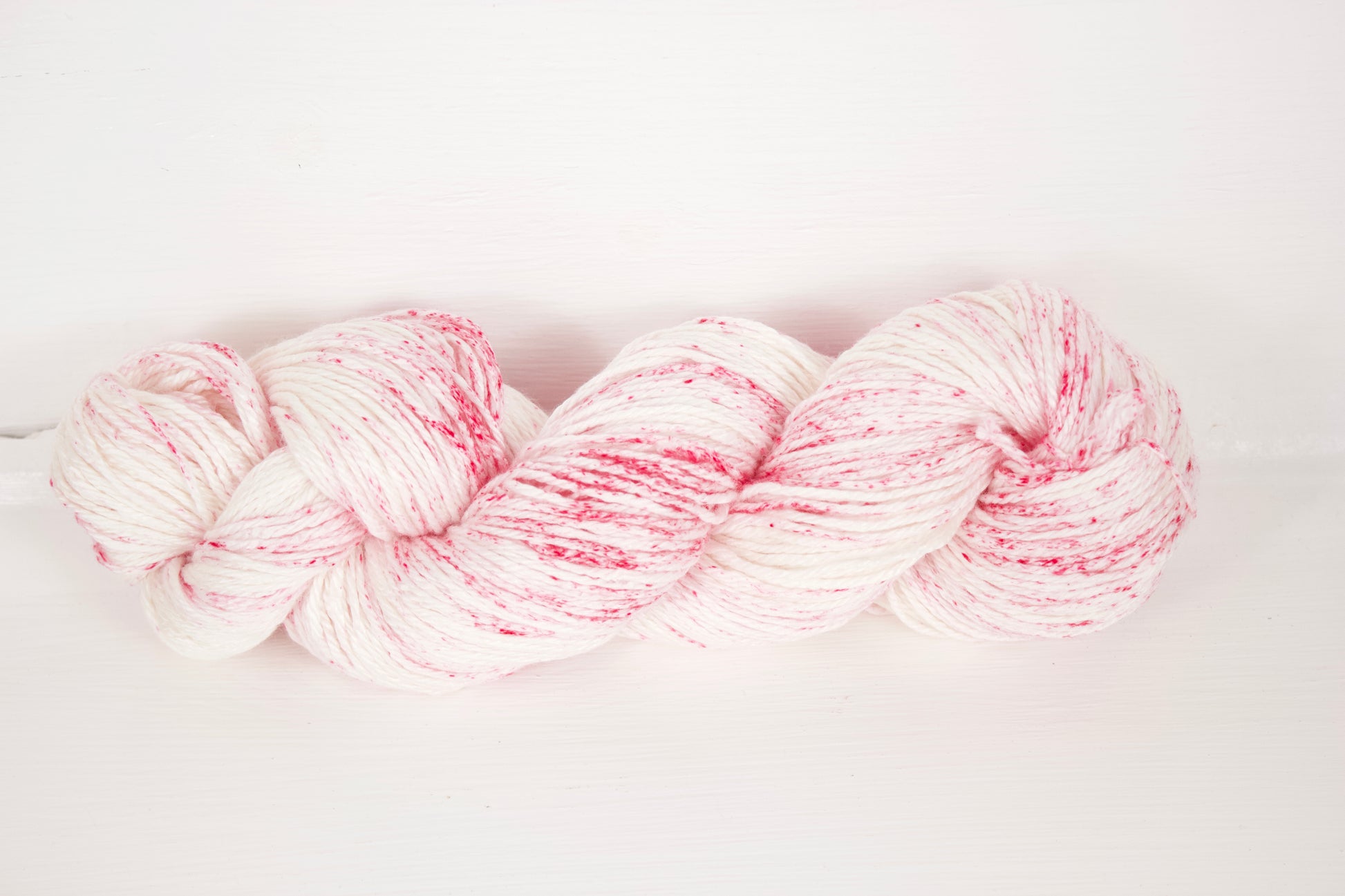 Creamy white base with hot pink speckles, this photo shows the whole skein