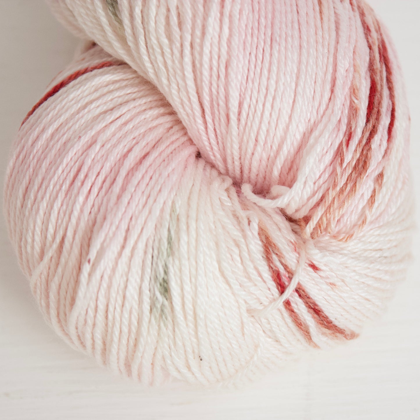 Cinnamon Sage Rose on Albireo is a creamy white base with tints of light pink and dashes of red-brown, and burgundy with purple halos, and strikes of sage green.